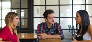 portrait serious student friends sitting table talking